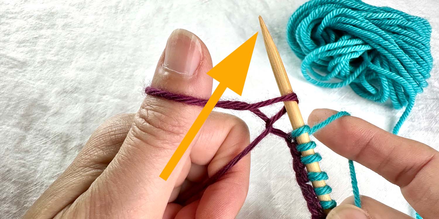 Needle in right hand, pointing upwards and going through twisted loop on left thumb. Directional arrow shows path needle took.