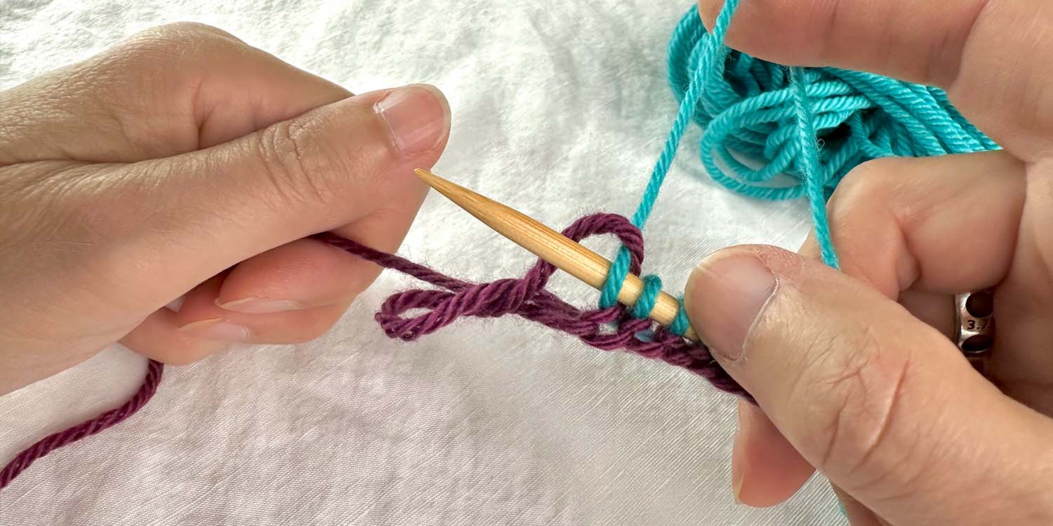 Cast on stitches on needle in right hand and left hand holding tail yarn. A loop of yarn has just dropped off the left thumb and is dangling close to cast on stitches.