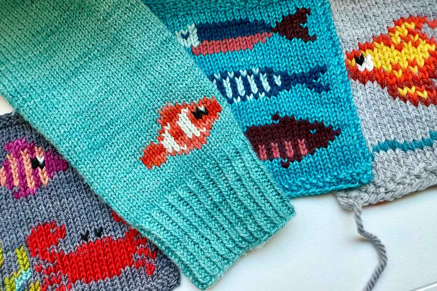 Swatches and a sweater sleeve all adorned with duplicate stitch fish and sea creatures.