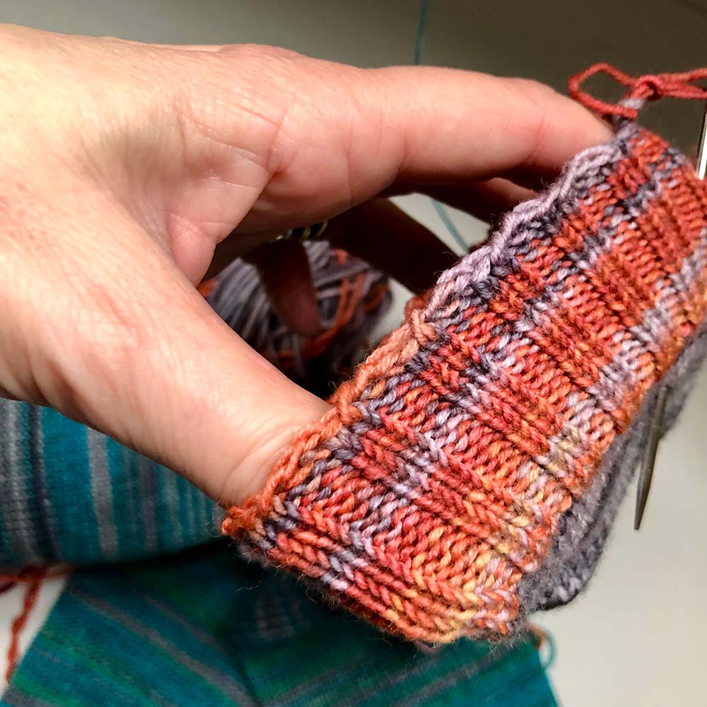 2x2 knitted sock cuff with hand inside stretching the cuff to show off the bind off.